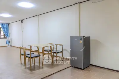 Spacious dining area with modern fridge and wooden table set in open layout apartment.