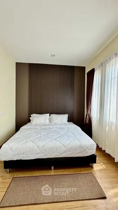 Spacious bedroom with elegant decor and large windows for natural light.