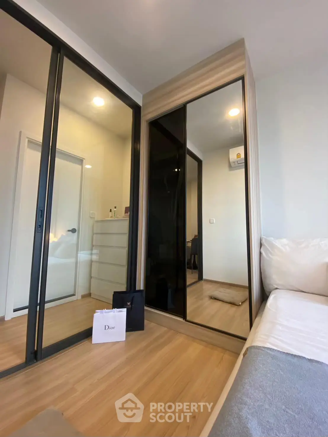 Modern bedroom with mirrored wardrobe and wooden flooring