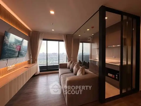 Modern living room with large windows and city view, featuring sleek design and cozy seating.