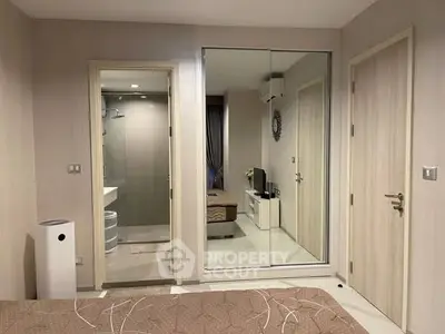 Modern bedroom with mirrored closet and en-suite bathroom in stylish apartment.