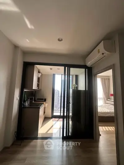 Modern apartment with open kitchen and bedroom, featuring city view and natural light.