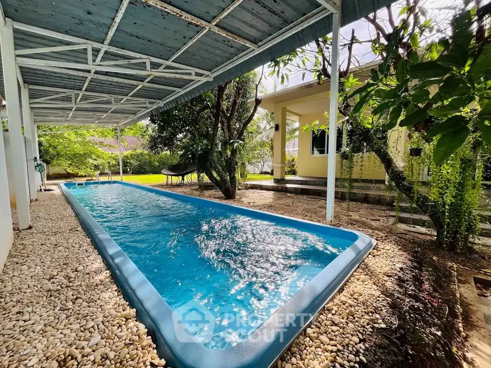 Charming backyard with a long swimming pool and lush greenery, perfect for relaxation and entertainment.