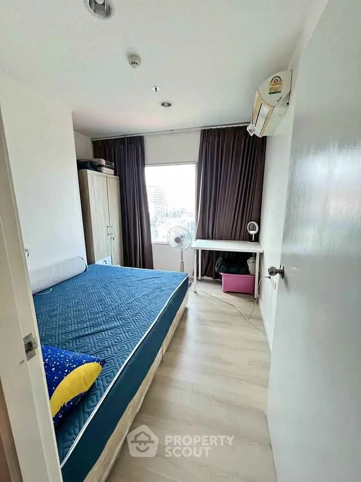 Cozy bedroom with large window and modern furnishings, perfect for urban living.