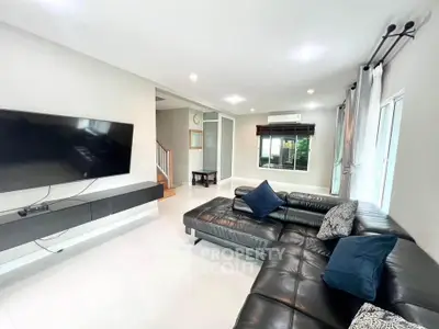 Spacious modern living room with sleek black leather sectional and wall-mounted TV