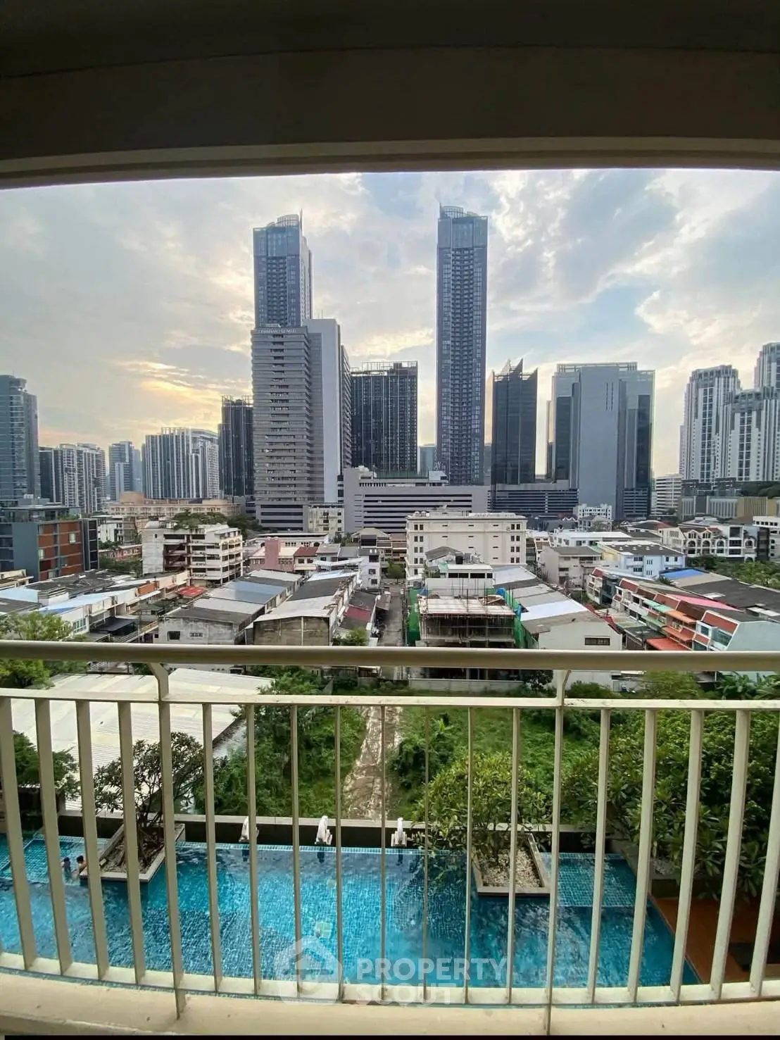 Stunning cityscape view from a high-rise balcony overlooking a pool and skyline.