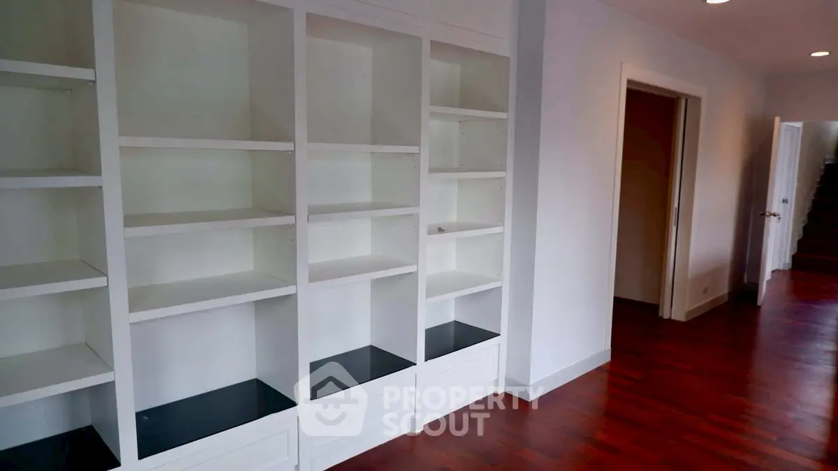 Spacious interior with built-in shelving and hardwood floors, ideal for modern living.