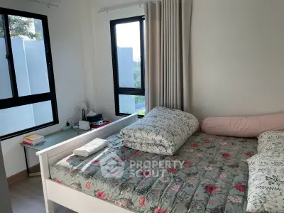 Cozy bedroom with floral bedding and natural light from large windows.