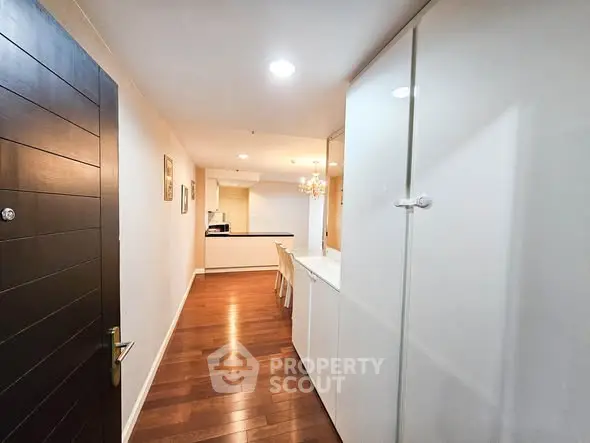 Spacious hallway leading to a modern kitchen with wooden flooring and sleek cabinetry.