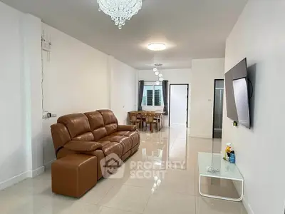Spacious modern living room with leather sofa and wall-mounted TV in a bright open layout.