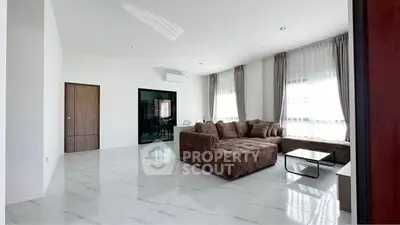 Spacious modern living room with large windows and stylish brown sectional sofa.