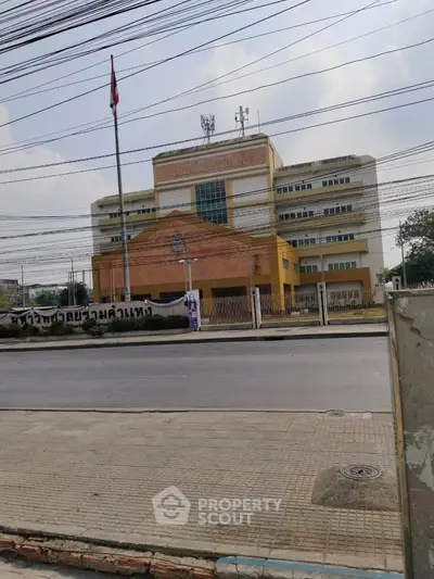 Modern multi-story building with a flagpole and clear sky view.