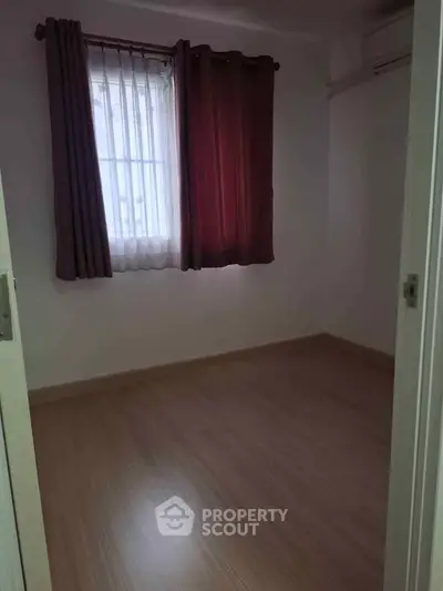 Cozy empty room with wooden flooring and window with red curtains, perfect for customization.