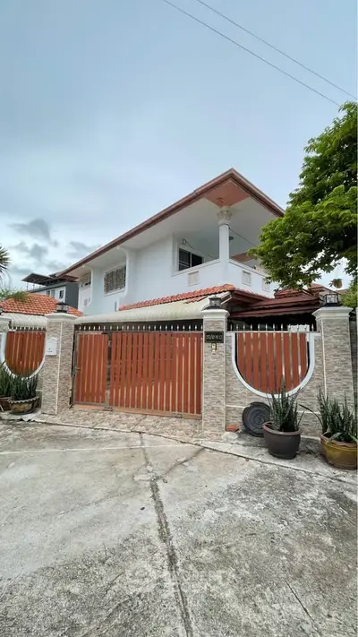 Charming two-story house with gated entrance and lush greenery