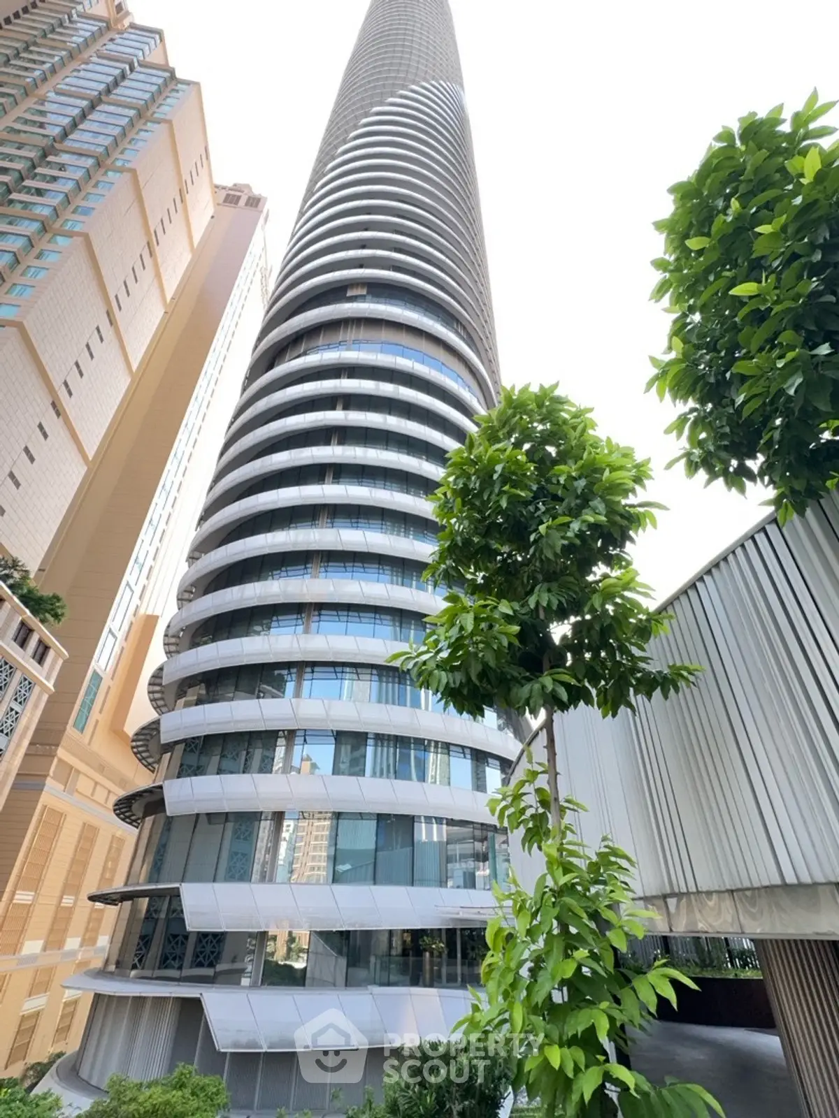Stunning modern skyscraper with unique circular design and lush greenery in urban setting.