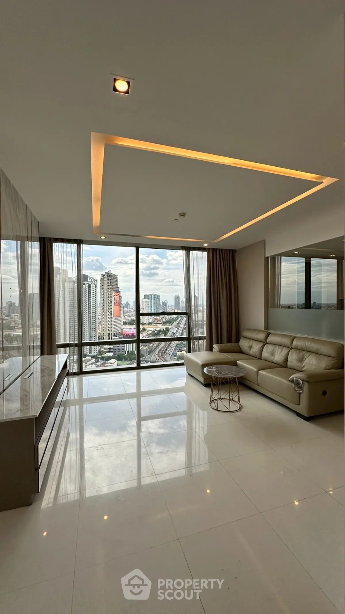 Spacious modern living room with panoramic city view and sleek furnishings.