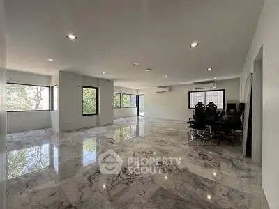 Spacious modern living room with marble flooring and large windows offering natural light.