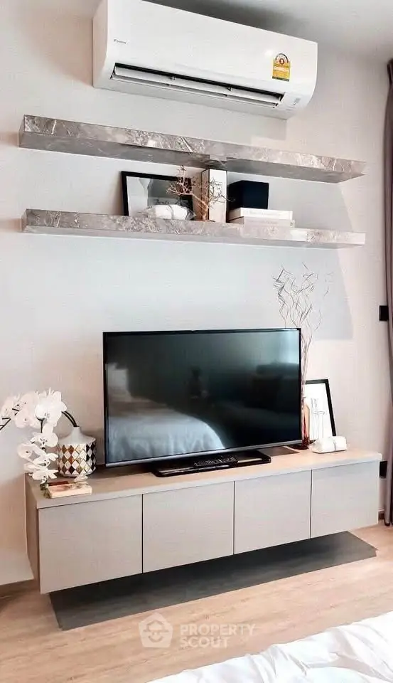 Modern living room with sleek TV unit and stylish wall shelves under air conditioning unit.
