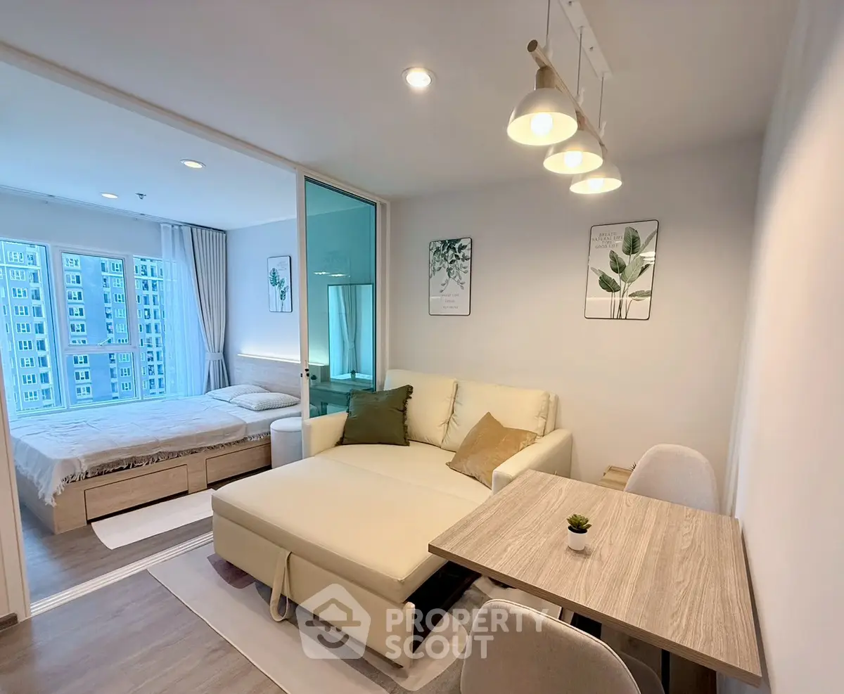 Modern living room with cozy sofa and dining area, adjacent to a bright bedroom with large windows.