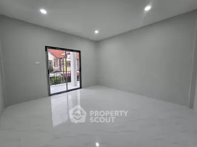 Spacious empty room with large window and balcony access, perfect for customization.