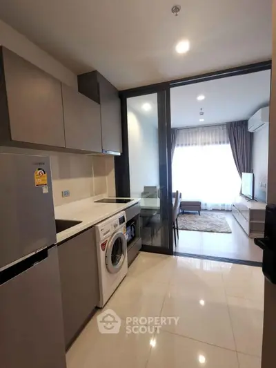 Modern kitchen with washing machine and open layout leading to cozy living room.