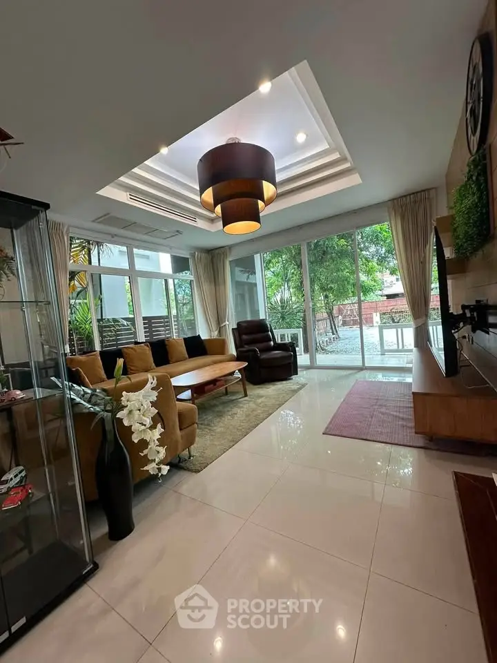 Spacious living room with modern decor and large windows offering garden views.