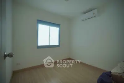 Spacious empty bedroom with wooden flooring and air conditioning