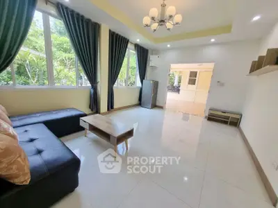 Spacious living room with modern decor and large windows offering garden views.