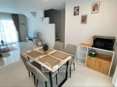 Modern dining area with elegant table set and cozy living room in open layout apartment.