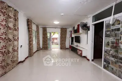 Spacious living room with large windows and elegant curtains, perfect for family gatherings.