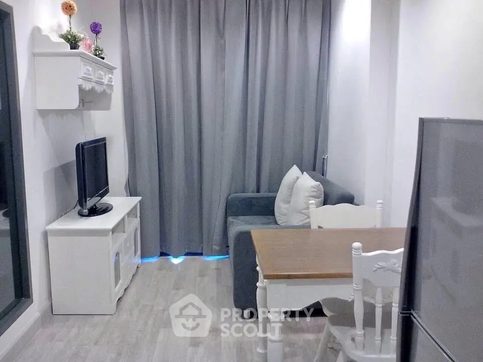 Cozy living room with modern decor, featuring a small dining area and a compact entertainment setup.