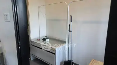 Compact storage area with modern design and cleaning tools in a real estate unit.