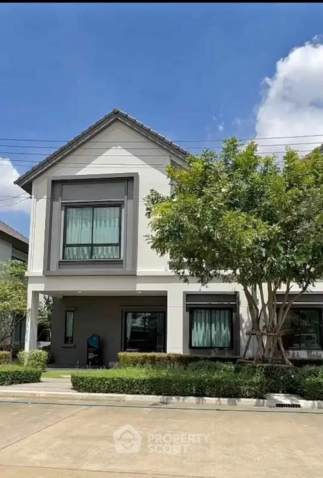 Modern two-story house with lush greenery and clear blue sky