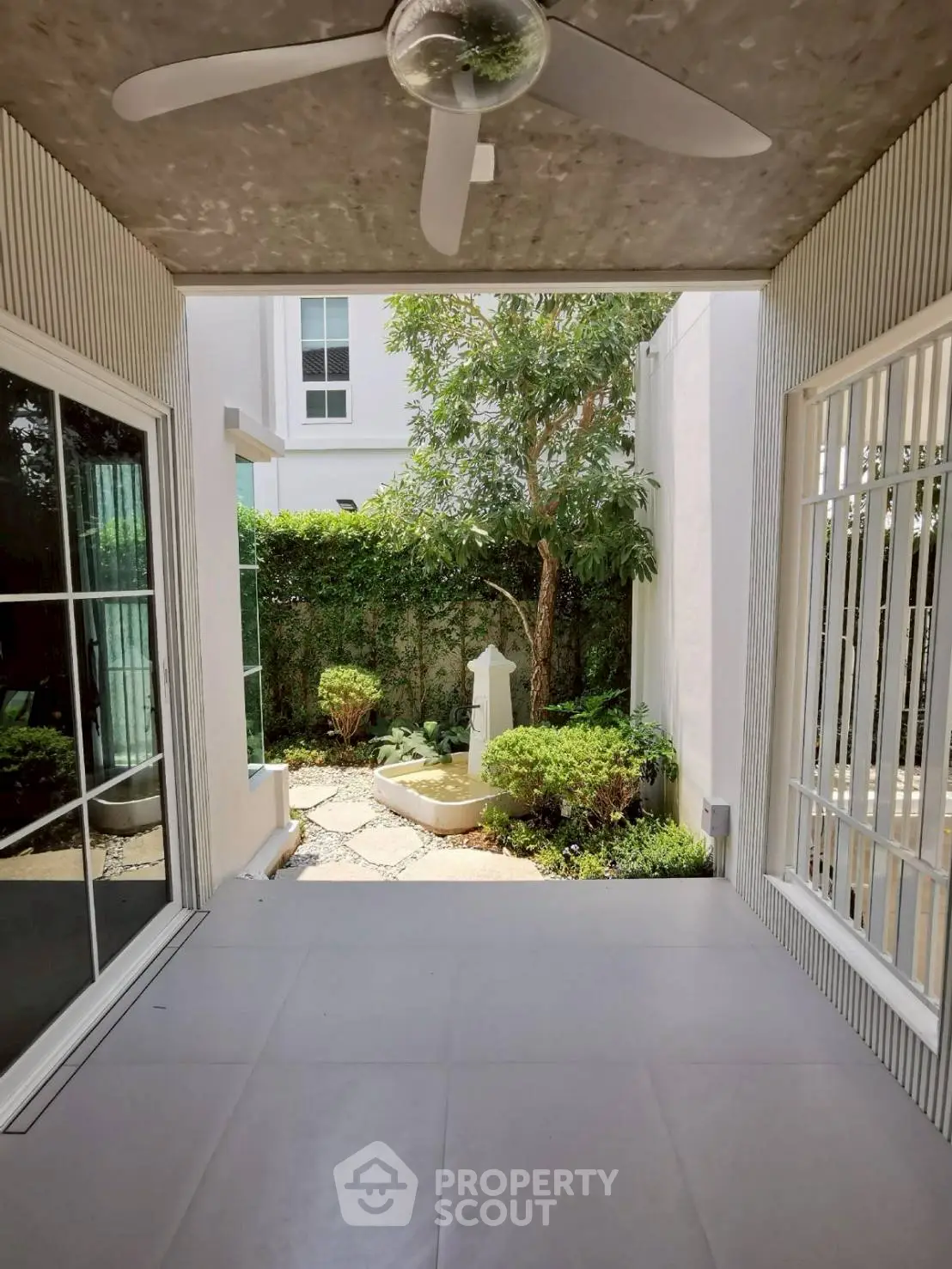 Charming patio with ceiling fan overlooking lush garden in modern home