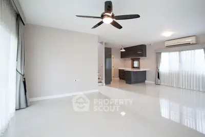 Spacious modern living room with ceiling fan and open kitchen layout