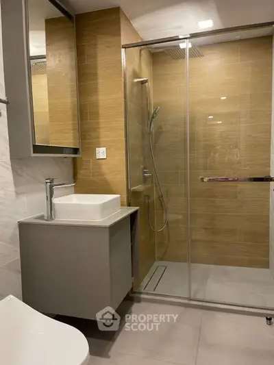 Modern bathroom with glass shower and sleek vanity in contemporary home.