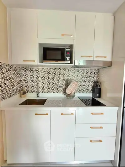 Modern compact kitchen with sleek white cabinets and mosaic backsplash