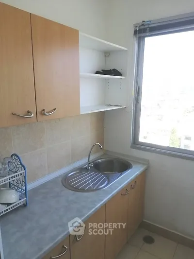Compact kitchen with window view and wooden cabinets