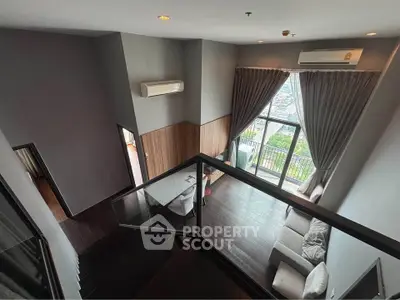 Spacious modern living room with high ceiling and large windows offering stunning city views.