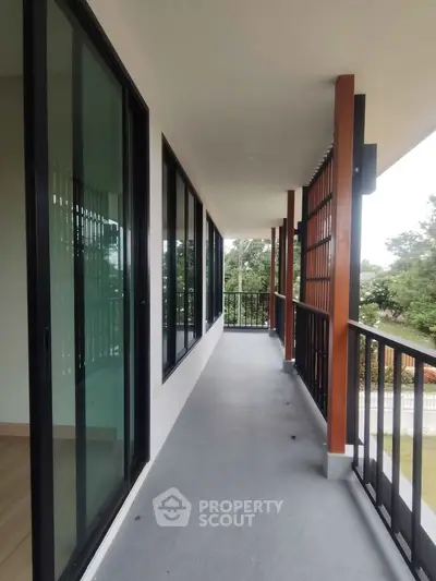 Spacious balcony with modern railing and large glass doors offering serene views.