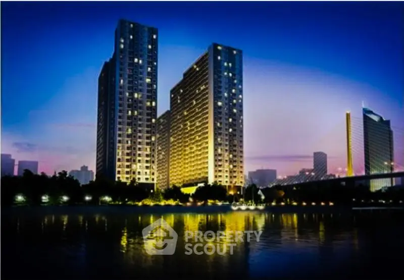 Stunning night view of modern high-rise buildings by the river with cityscape backdrop.
