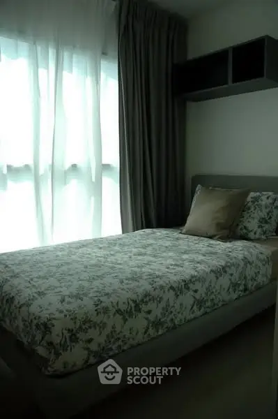 Cozy bedroom with floral bedding and natural light through sheer curtains.