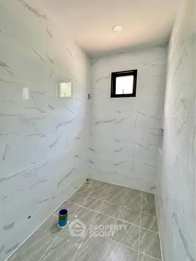 Minimalist bathroom with marble tiles and small window