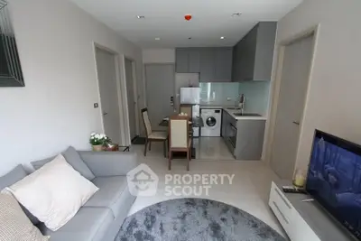 Modern living room with open kitchen, cozy sofa, and dining area in a stylish apartment.