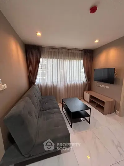 Modern living room with sleek furniture and large window, perfect for relaxation and entertainment.