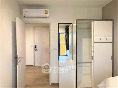 Modern bedroom with sleek wardrobe and air conditioning in a stylish apartment.