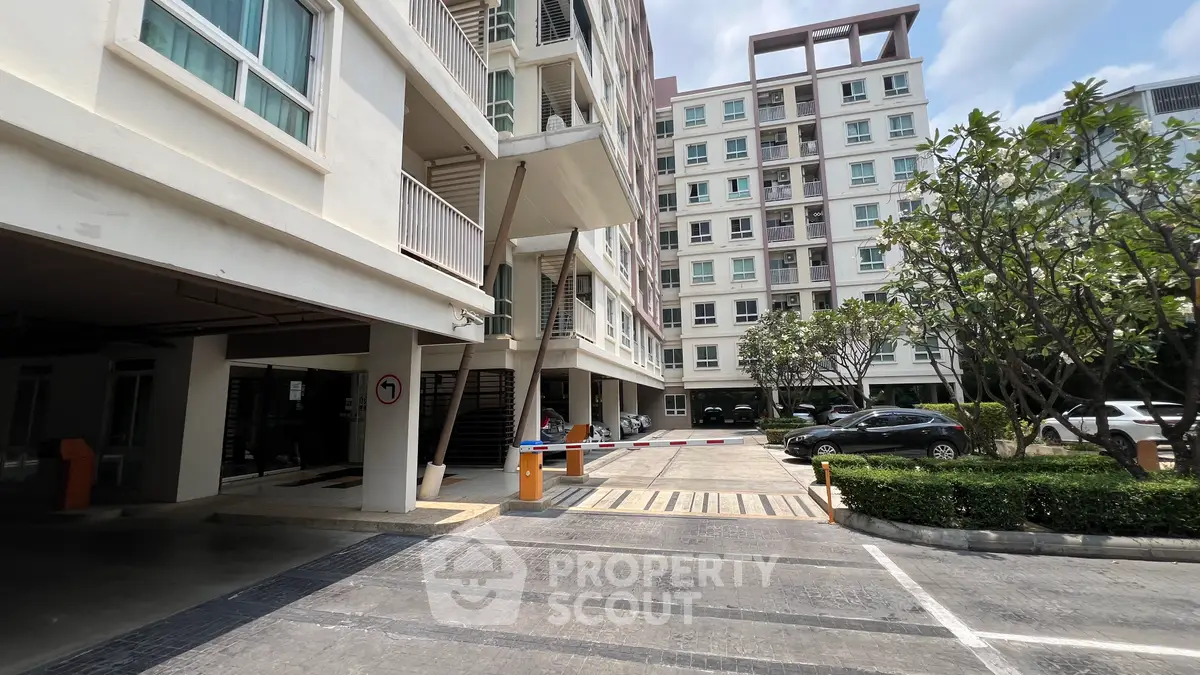 Modern apartment building exterior with parking area and lush greenery