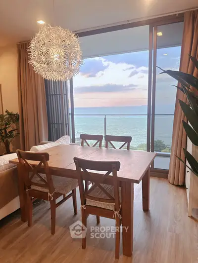 Stunning ocean view from modern dining area with elegant chandelier and wooden furniture.
