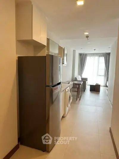 Modern apartment interior with open layout, featuring kitchen appliances and a cozy living area with natural light.