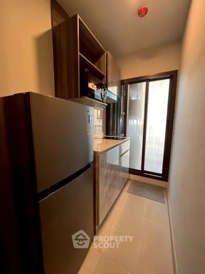 Modern kitchen with sleek cabinetry and large fridge in compact layout.